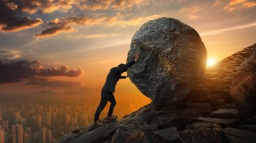 Man trying to roll a boulder up a hill